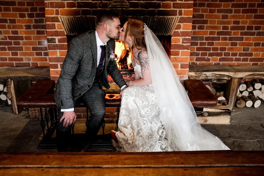 Micklefield Hall weddings, bride and groom kissing in front of fire in garden room