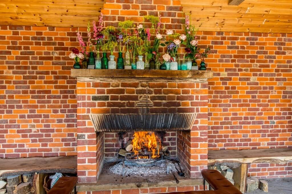 Micklefield Hall Garden room with lit fire in fire place with flowers on the mantel piece