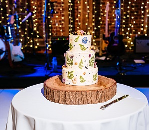 Beautiful cake made by the bride with white icing and vibrant florals. Topped with two bees
