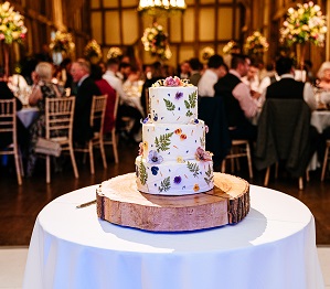 Beautiful cake made by the bride with white icing and vibrant florals. Topped with two bees