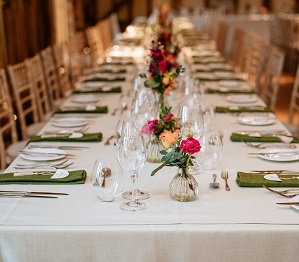 dining table in barn with white table cloths and olive green napkins