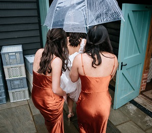 bride and bridemaids getting inside out of the rain before the ceremony