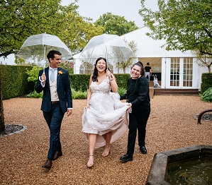bride and groom under umbrellas laughing in the rain on their rainy wedding day at micklefield hall