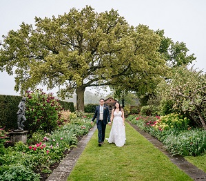 bride and groom walking through gardens 