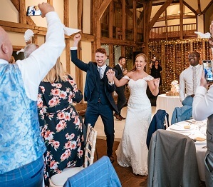 Bride and groom entrance into wedding breakfast, guests waving napkins in the air