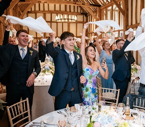 Bride and groom entrance into wedding breakfast, guests waving napkins in the air